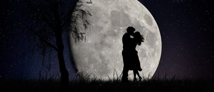 A couple hugging at night and full moon behind.